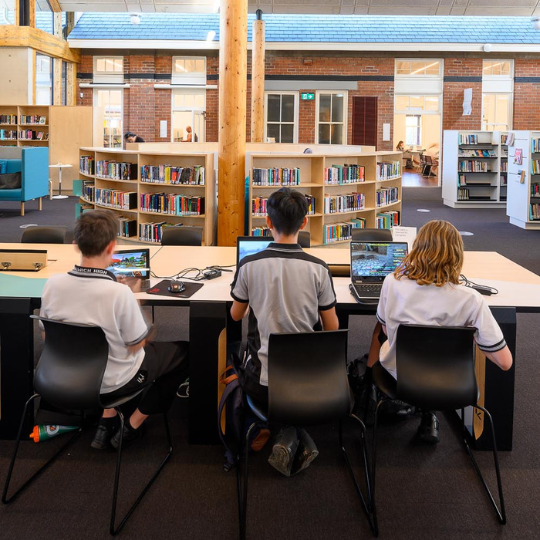 Three students working on their computers at the library